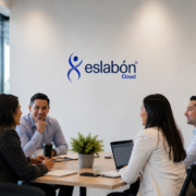 Equipo de trabajo reunido en una sala de juntas moderna con laptop y plantas, frente al logo de Eslabón Cloud