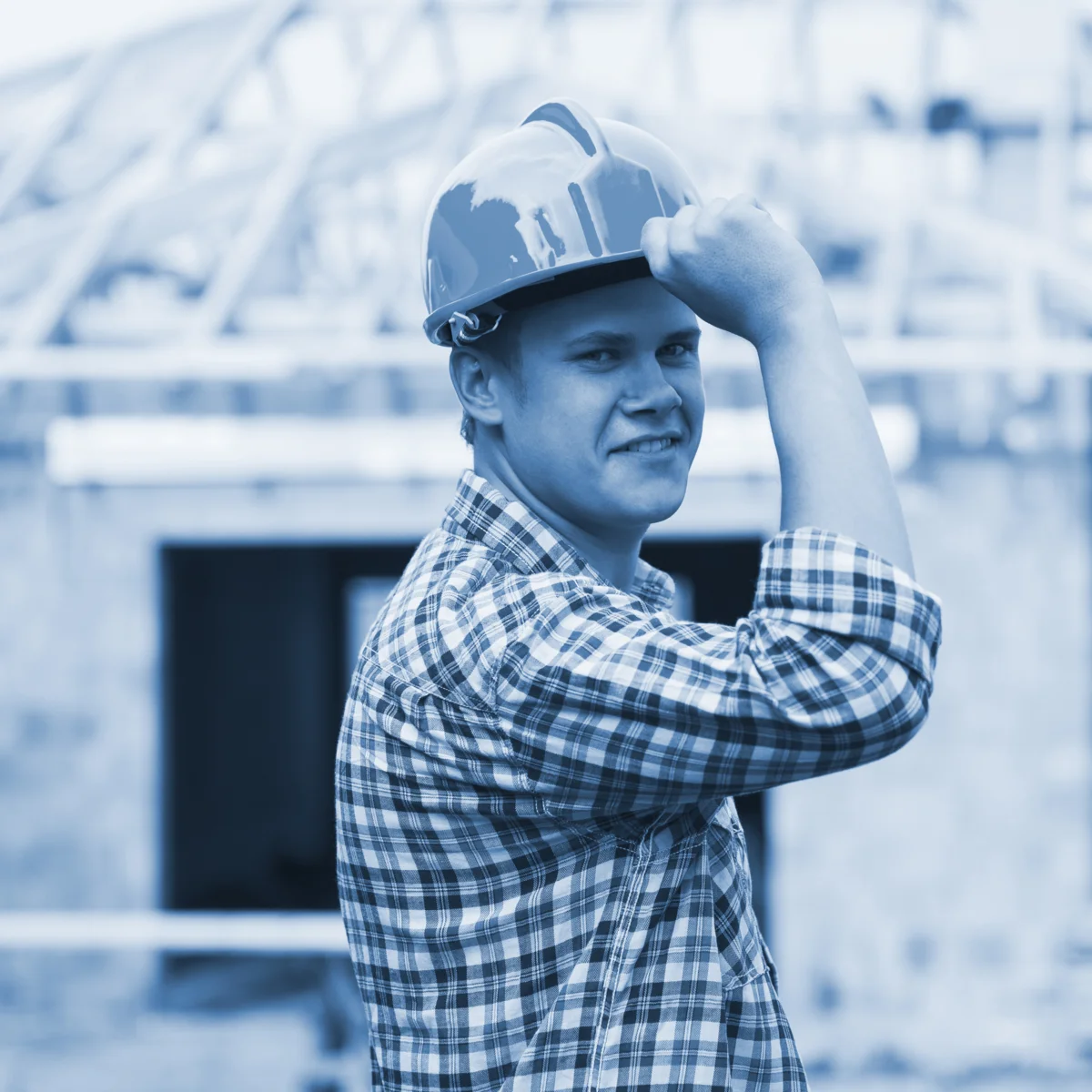 Trabajador de construccion sonriendo mientras sostiene su casco puesto